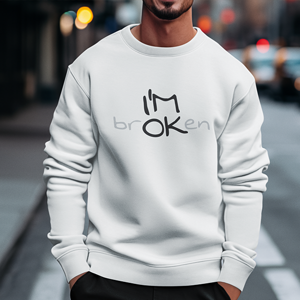 I'M brOKen Premium Sober Apparel worn by a man in a white sweatshirt, featuring a hidden "I'M OK" message that symbolizes resilience, recovery, and hope through life's challenges.