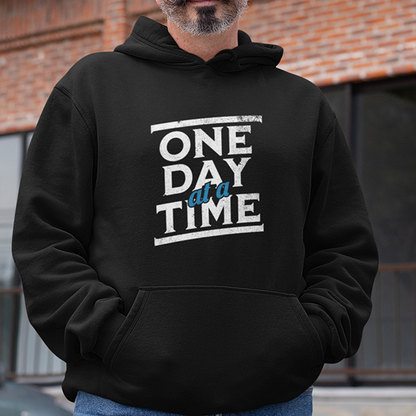 One Day At A Time Premium Sober Apparel worn by a woman in a white hoodie, displaying a meaningful reminder that every sober day is a victory worth celebrating.