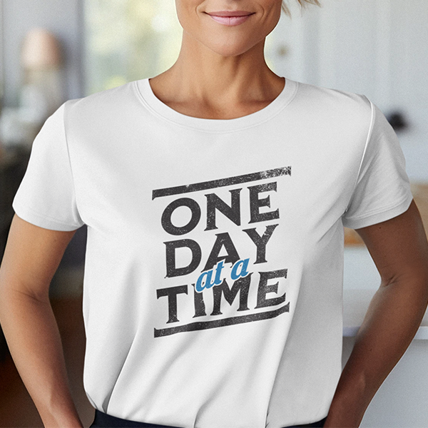 One Day At A Time Premium Sober Apparel worn by a woman in a white t-shirt, showcasing a simple yet powerful reminder to stay present and focused on today's recovery journey.
