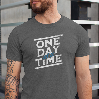 One Day At A Time Premium Sober Apparel worn by a man in a sports gray t-shirt, featuring a timeless recovery message that reminds us lasting change happens one day at a time.