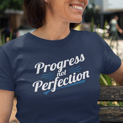 Woman wearing Progress Not Perfection Premium Sober Apparel t-shirt, smiling outdoors.